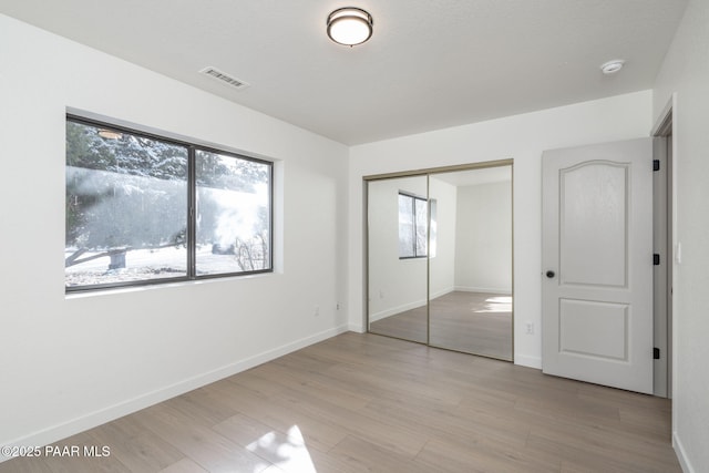 unfurnished bedroom featuring light wood-type flooring and a closet