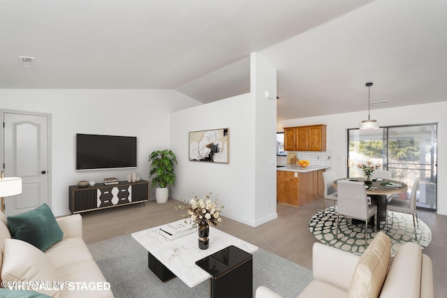 living room with light hardwood / wood-style flooring and vaulted ceiling