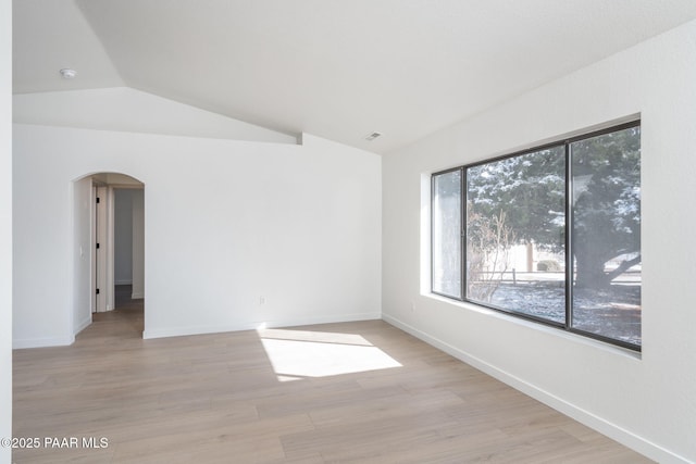 spare room with lofted ceiling and light hardwood / wood-style flooring