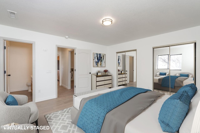 bedroom featuring multiple closets and light hardwood / wood-style floors