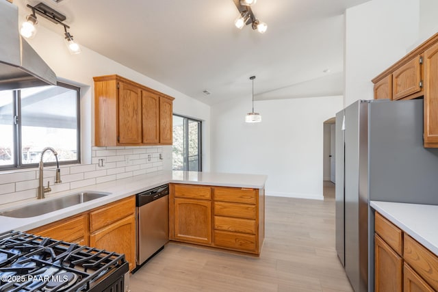 kitchen featuring sink, vaulted ceiling, kitchen peninsula, pendant lighting, and stainless steel appliances