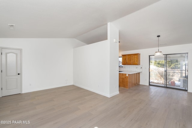 unfurnished living room featuring lofted ceiling and light wood-type flooring