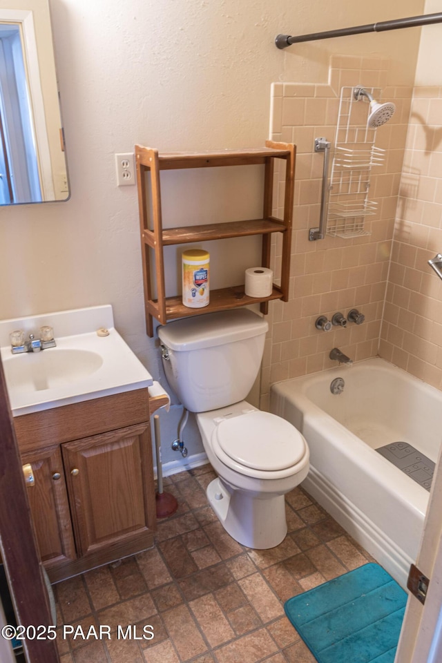 bathroom featuring vanity, baseboards, stone finish floor, shower / tub combination, and toilet