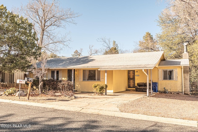 ranch-style home featuring driveway, an attached carport, and a chimney