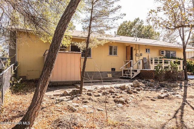 rear view of house with crawl space, a deck, and fence