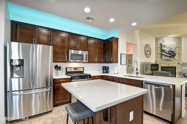 kitchen featuring a center island, sink, a kitchen bar, dark brown cabinetry, and stainless steel appliances