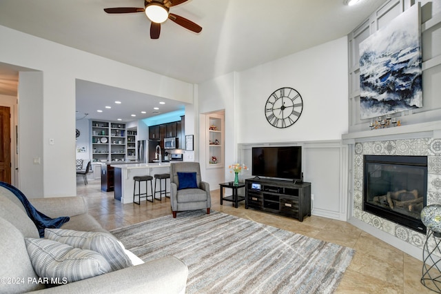 tiled living room featuring a fireplace, ceiling fan, and built in features