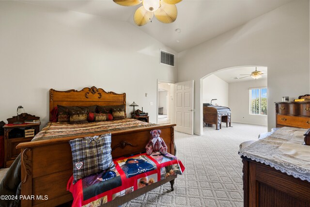 carpeted bedroom with ceiling fan and high vaulted ceiling