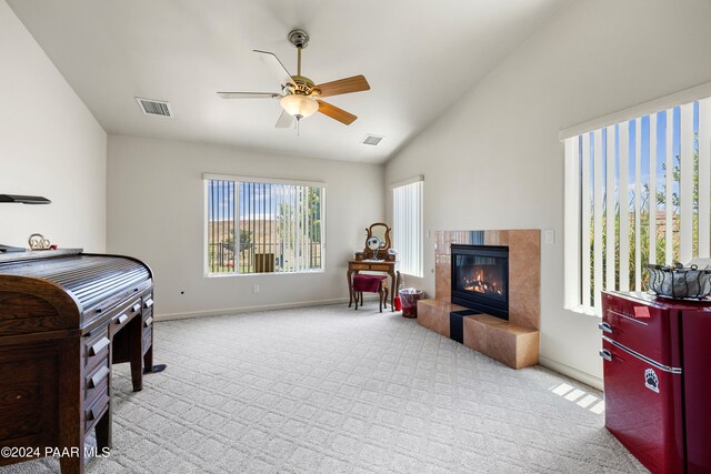 carpeted bedroom featuring a tile fireplace, ceiling fan, and lofted ceiling