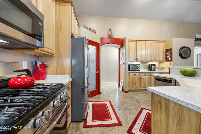 kitchen featuring light brown cabinets, light stone counters, and stainless steel appliances