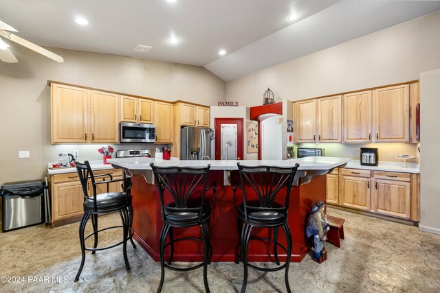 kitchen with ceiling fan, a center island, stainless steel appliances, lofted ceiling, and a kitchen bar