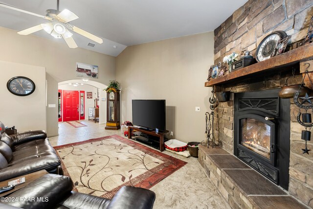 living room featuring a stone fireplace, ceiling fan, and lofted ceiling