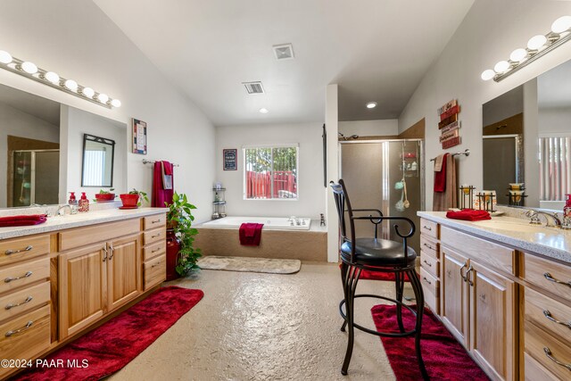 bathroom with vanity, independent shower and bath, and vaulted ceiling