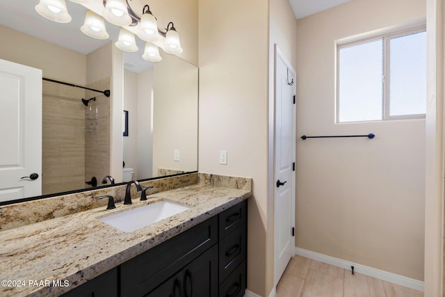 bathroom with a tile shower, tile patterned flooring, vanity, and toilet