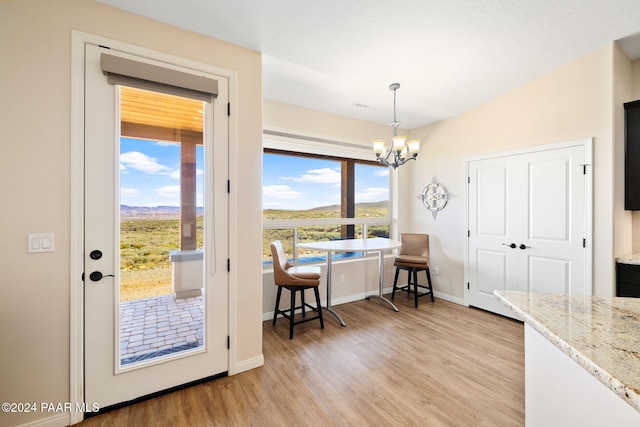 doorway to outside featuring breakfast area, an inviting chandelier, and light wood-type flooring