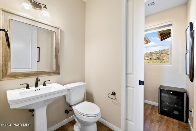 bathroom featuring wine cooler, hardwood / wood-style floors, and toilet