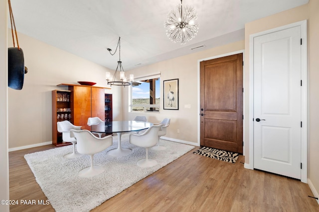 dining space with light hardwood / wood-style flooring and an inviting chandelier