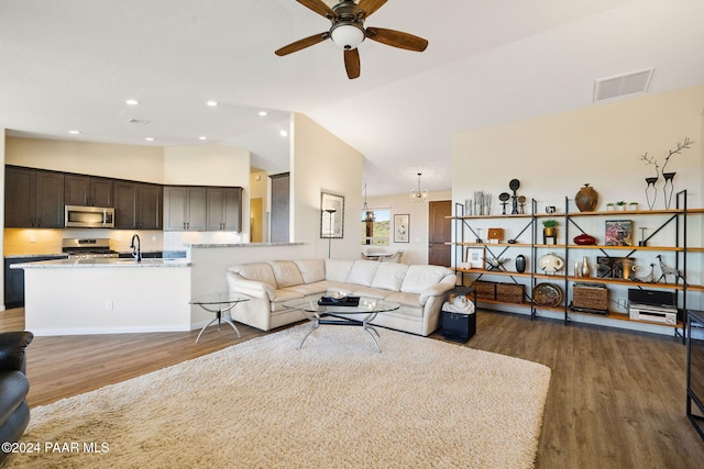 living room with ceiling fan, dark hardwood / wood-style flooring, sink, and vaulted ceiling