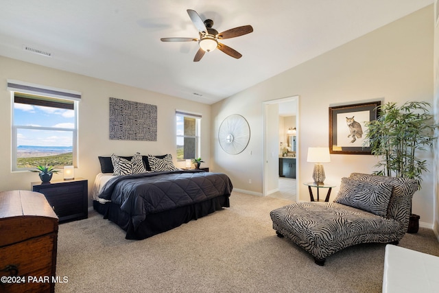 bedroom featuring light colored carpet, ensuite bath, multiple windows, and lofted ceiling