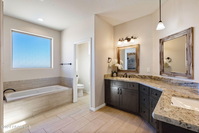 bathroom with tiled tub, hardwood / wood-style floors, vanity, and toilet