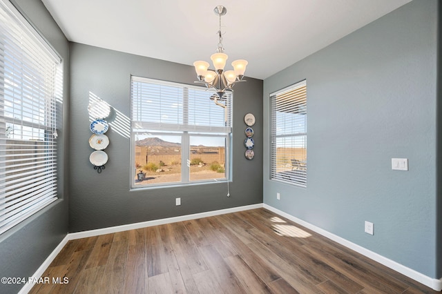 unfurnished dining area featuring a chandelier and wood-type flooring