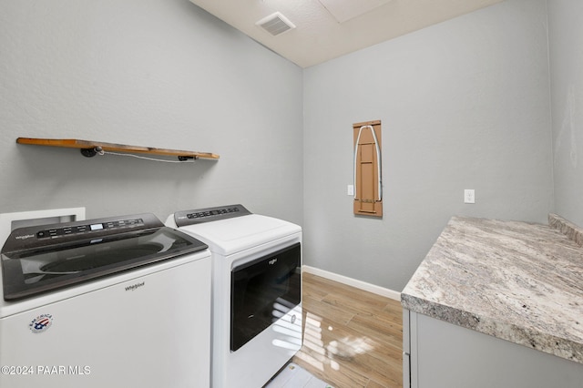 laundry room featuring washer and clothes dryer and light wood-type flooring