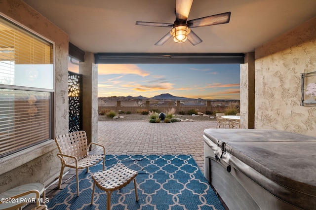 patio terrace at dusk with ceiling fan and a hot tub