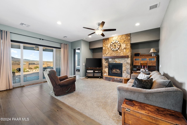 living room with a stone fireplace, ceiling fan, and wood-type flooring