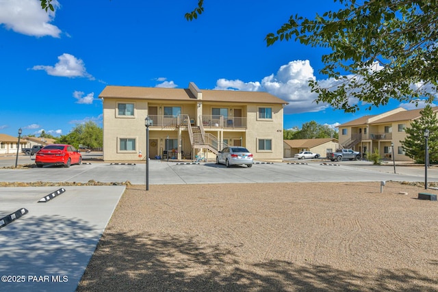 view of property with a residential view, uncovered parking, and stairway