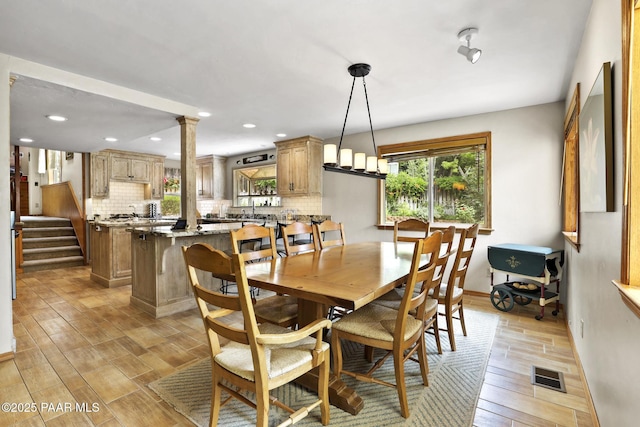 dining space with light hardwood / wood-style flooring and decorative columns