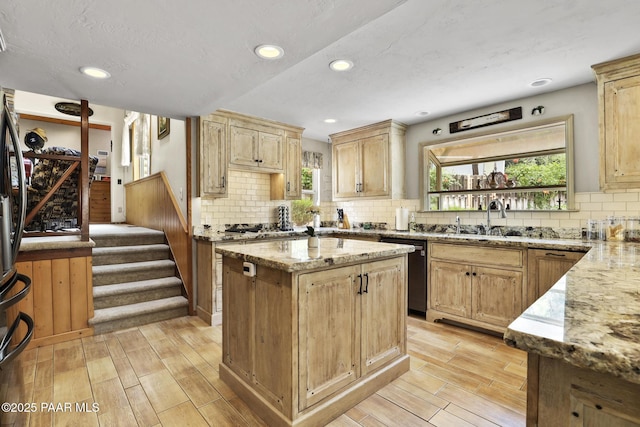 kitchen with sink, light stone countertops, a center island, and dishwasher