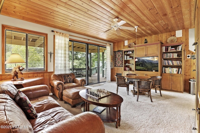 carpeted living room featuring wood ceiling, ceiling fan, and wooden walls