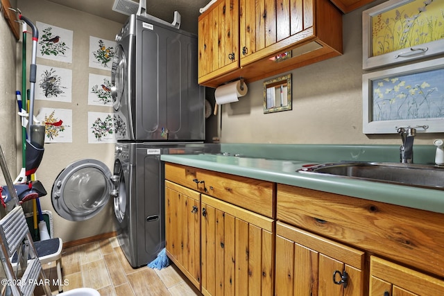 laundry area featuring stacked washer and dryer, cabinets, and sink