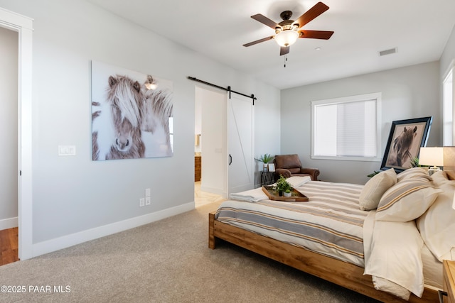 carpeted bedroom featuring visible vents, a ceiling fan, ensuite bath, a barn door, and baseboards