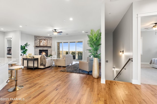 living room with recessed lighting, ceiling fan, a fireplace, and light wood finished floors