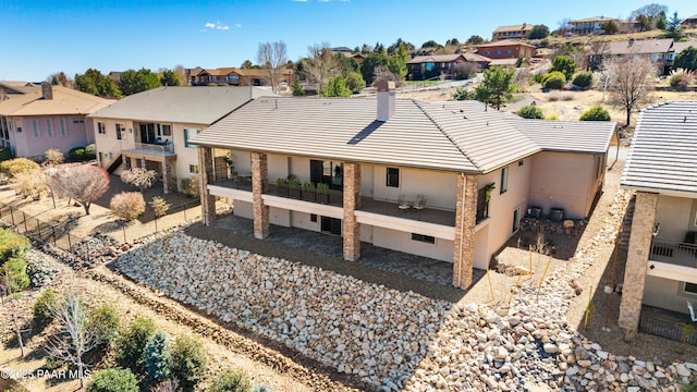 back of property featuring fence, a residential view, a balcony, a chimney, and a tiled roof