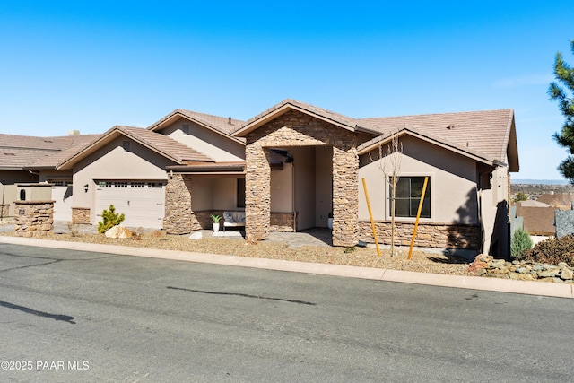 view of front of home featuring stucco siding, stone siding, a garage, and a tile roof