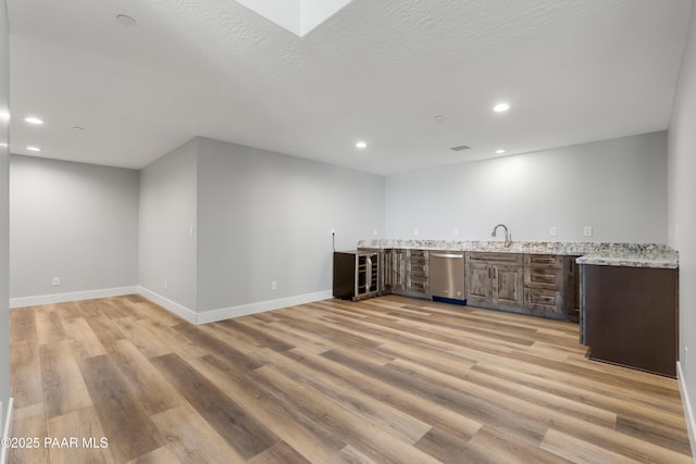 bar featuring dishwasher, wet bar, light wood-style floors, and a sink