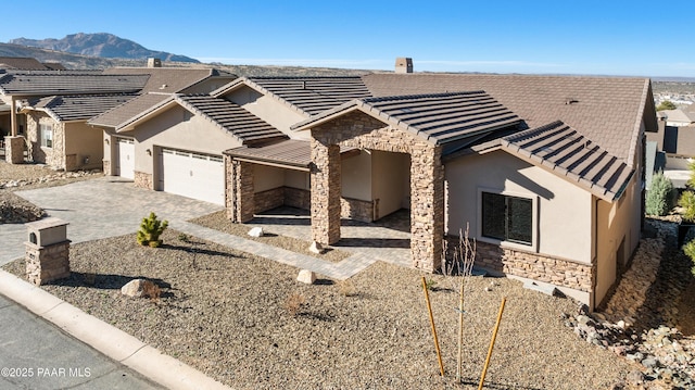 view of front of house featuring stone siding, stucco siding, a tiled roof, and decorative driveway