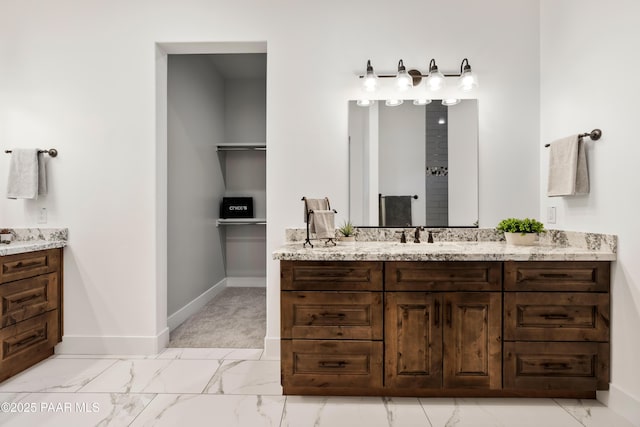 bathroom with two vanities, baseboards, marble finish floor, and a sink