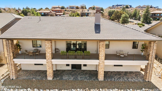 back of property with a tile roof, a patio area, and stucco siding