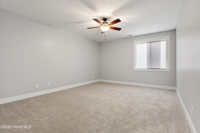 unfurnished room featuring light carpet, visible vents, a ceiling fan, and baseboards