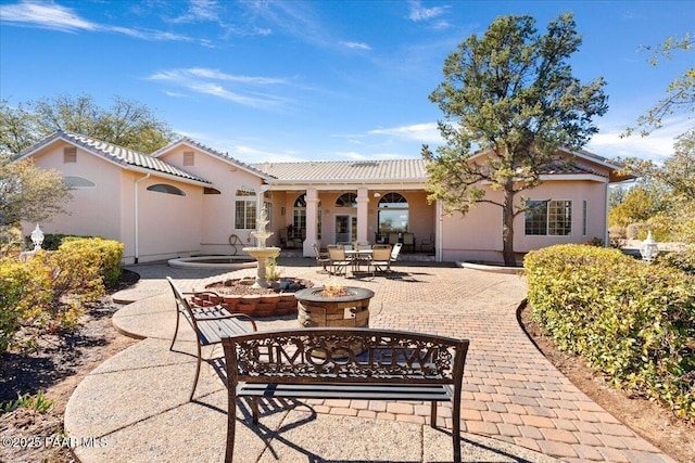 back of house featuring a patio, a tile roof, and stucco siding