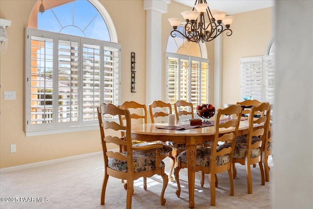 carpeted dining space featuring baseboards and an inviting chandelier