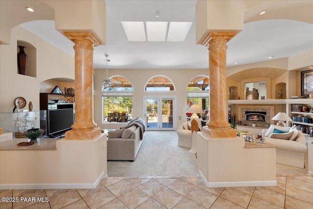 living room with a warm lit fireplace, light tile patterned flooring, decorative columns, and recessed lighting