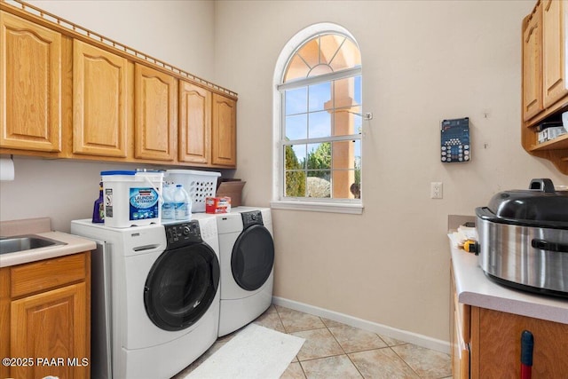 laundry room featuring light tile patterned floors, washer and clothes dryer, cabinet space, and baseboards