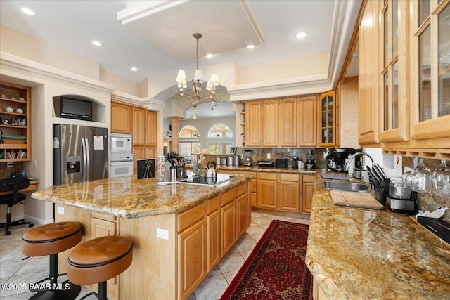 kitchen featuring white appliances, a breakfast bar, a sink, backsplash, and an island with sink