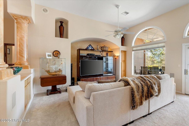 living area featuring light carpet, decorative columns, visible vents, ceiling fan, and a high ceiling