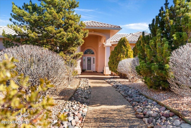 entrance to property featuring a tile roof and stucco siding