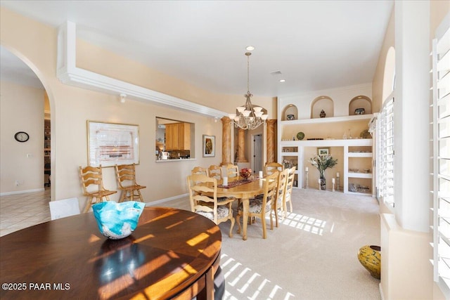 dining room featuring built in shelves, arched walkways, carpet floors, visible vents, and an inviting chandelier